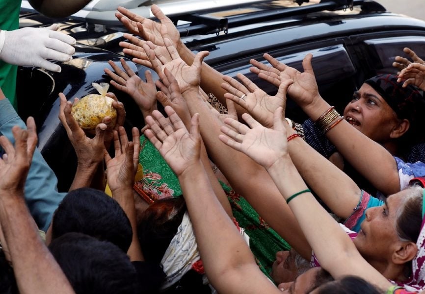 People reach for food aid in Karachi, Pakistan following a lockdown amid the coronavirus outbreak. REUTERS.